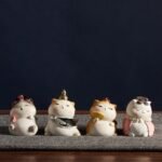 Set of 4 Chinese ancient style cat figurines displayed on grey table against dark background