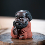 Main view of handcrafted red glaze Bodhidharma Zen tea pet on wooden tea tray