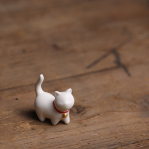 Main view of white ceramic lucky cat tea pet with red collar and golden bell