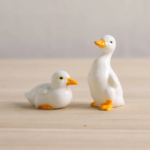 Set of 2 glazed ceramic duck tea pets displayed on light wood table