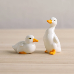 Set of 2 glazed ceramic duck tea pets displayed on light wood table