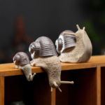 Handcrafted ceramic snail tea pet displayed on wooden bookshelf as home decor