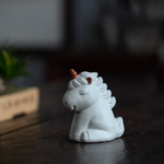 Cute ceramic unicorn tea pet placed on wooden tea table