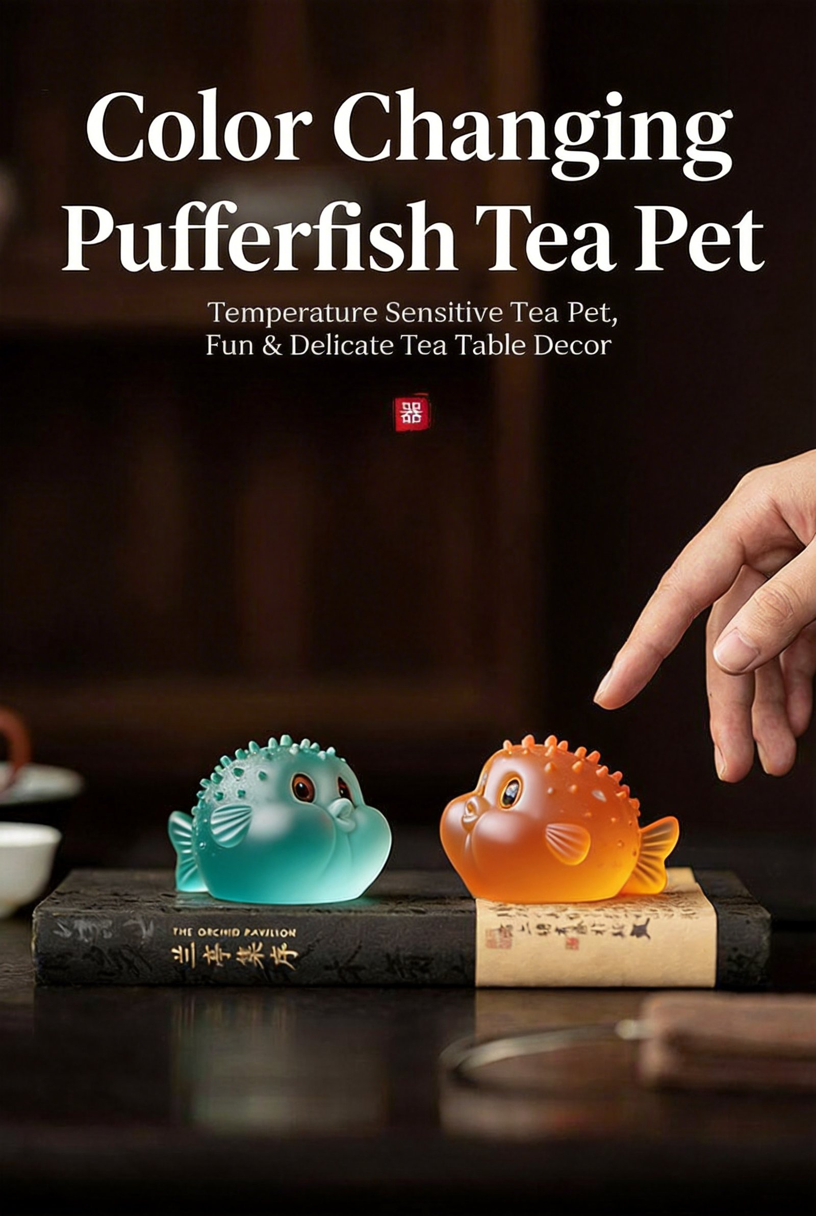 Orange and blue color changing pufferfish tea pets placed on books next to tea utensils