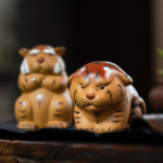 Handmade cute tiger zisha tea pet main product view, all three pose variants displayed on wood tea table