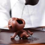 Reddish-brown handmade peeing boy ceramic tea pet on wooden tea tray