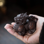 Hand held purple clay qilin tea pet showing detailed carving texture