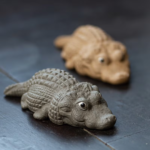 Handmade Yixing clay crocodile tea pet on dark wooden tea table, gray color