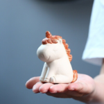 Main view of handmade Yixing clay unicorn tea pet with orange mane and off-white body