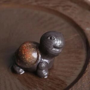 Handmade Yixing zisha cute turtle tea pet placed on wooden tea tray for gongfu tea ceremony
