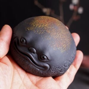 Hand holding yixing zisha lucky money toad tea pet to show portable size