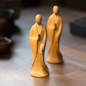 Handcrafted zen monk clay tea pet displayed on wooden tea table with tea ware background