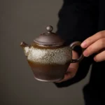 Handheld view of 180ml handcrafted ceramic clay teapot showing handle and spout