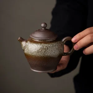 Handheld view of 180ml handcrafted ceramic clay teapot showing handle and spout