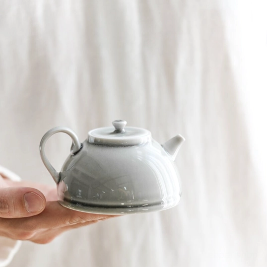 hand holding 200ml small celadon ceramic teapot to show size