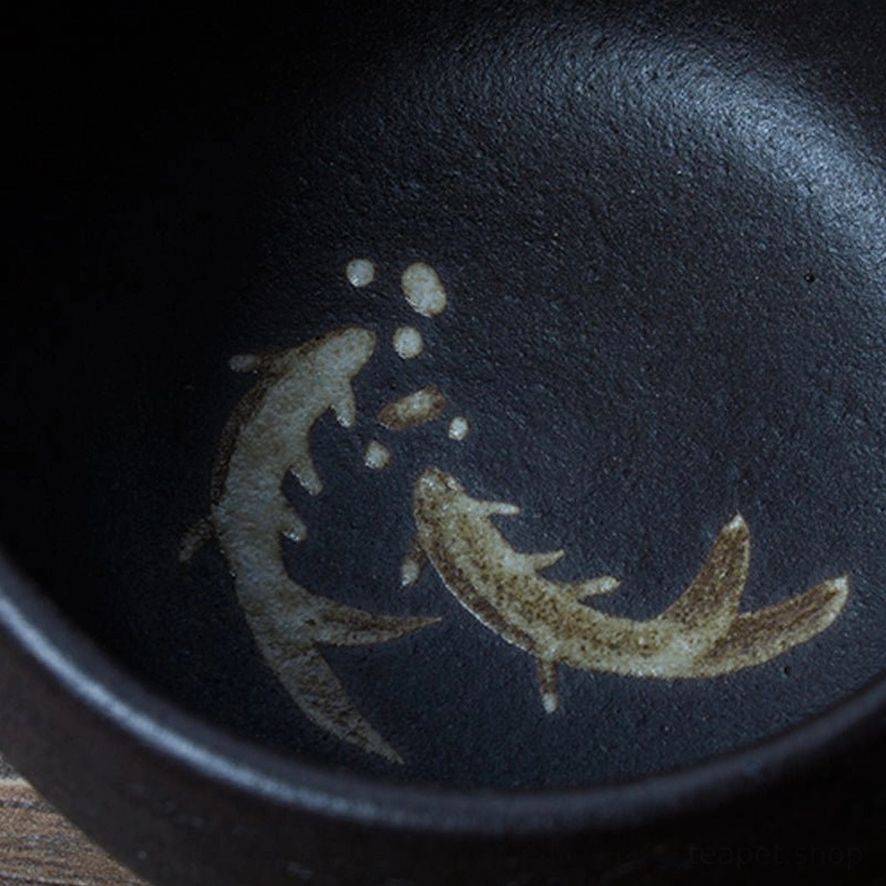 black ceramic tea cup filled with hot tea on a wooden table