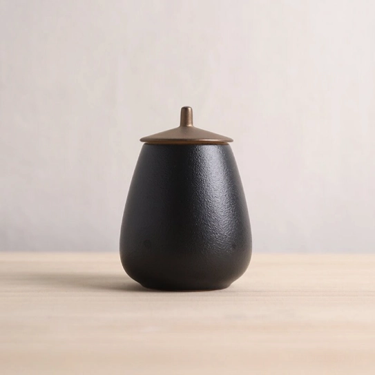 black pear shaped ceramic tea jar with bronze metal lid front view