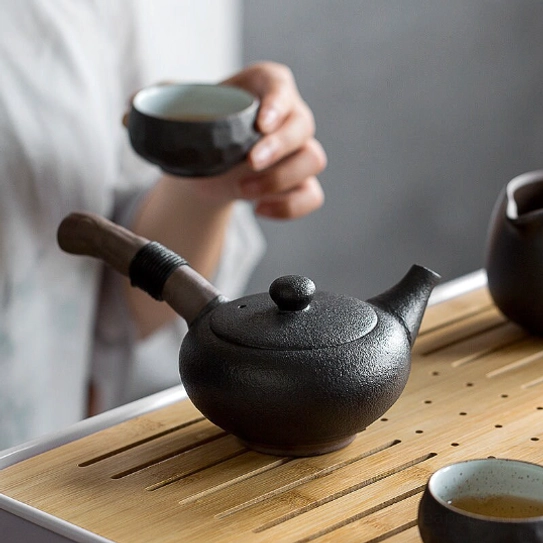 black kyusu teapot displayed with matcha and tea caddy on tea table