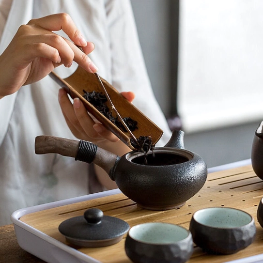 black kyusu teapot with tea cup set on traditional tea mat
