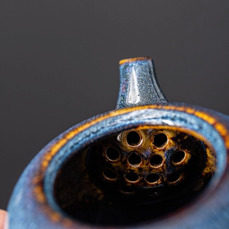 ergonomic handle of blue ceramic teapot held by hand showing size