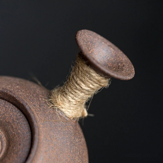 kyusu teapot resting on wooden table showing rustic brown finish
