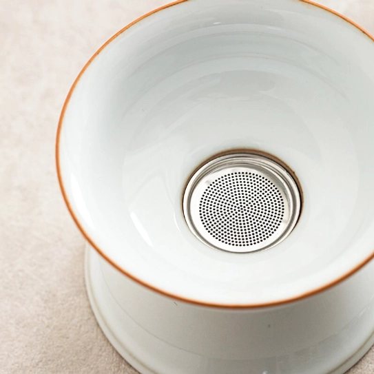 ceramic loose leaf tea strainer resting on base close up