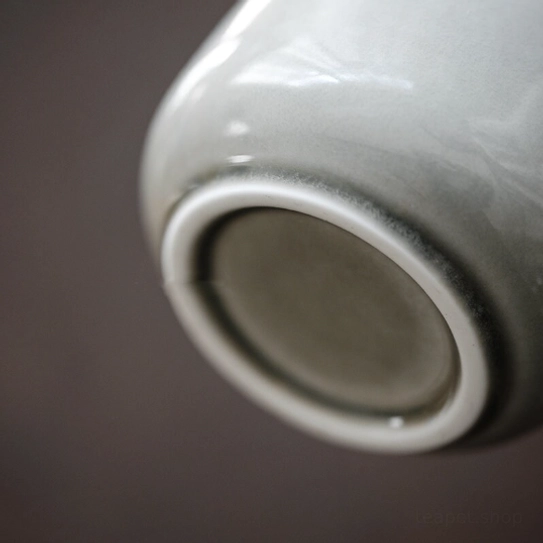 Ash green ceramic tea jar with bamboo lid placed on tea table with other tea wares