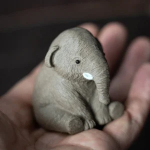 Hand holding palm-sized mini cute elephant tea pet showing compact size