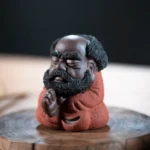 Main view of handcrafted red glaze cute Bodhidharma Zen tea pet on wooden tea tray