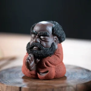 Main view of handcrafted red glaze cute Bodhidharma Zen tea pet on wooden tea tray