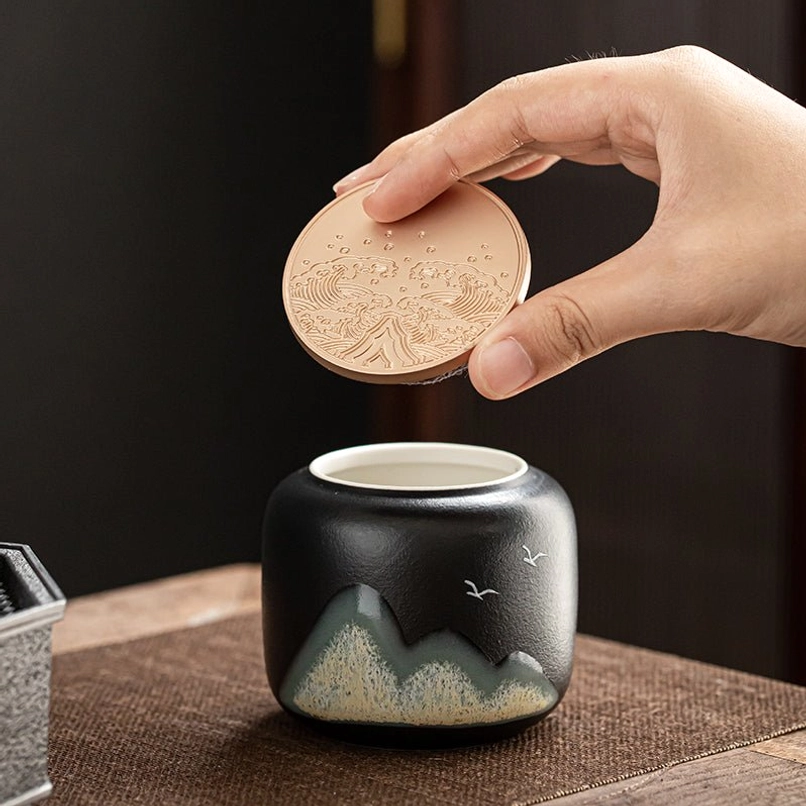 Full front view of hand-glazed mountain and bird landscape on the black tea jar
