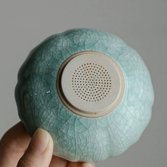 celadon green ceramic lotus loose leaf tea strainer resting on matching base