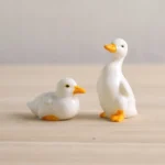 Set of 2 handcrafted glazed ceramic duck tea pets on light wood tea table