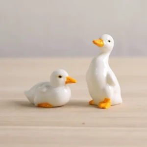 Set of 2 handcrafted glazed ceramic duck tea pets on light wood tea table