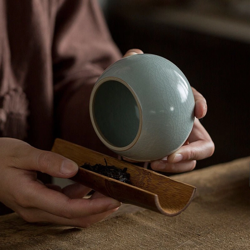 green ceramic tea jar held in hand to show size reference
