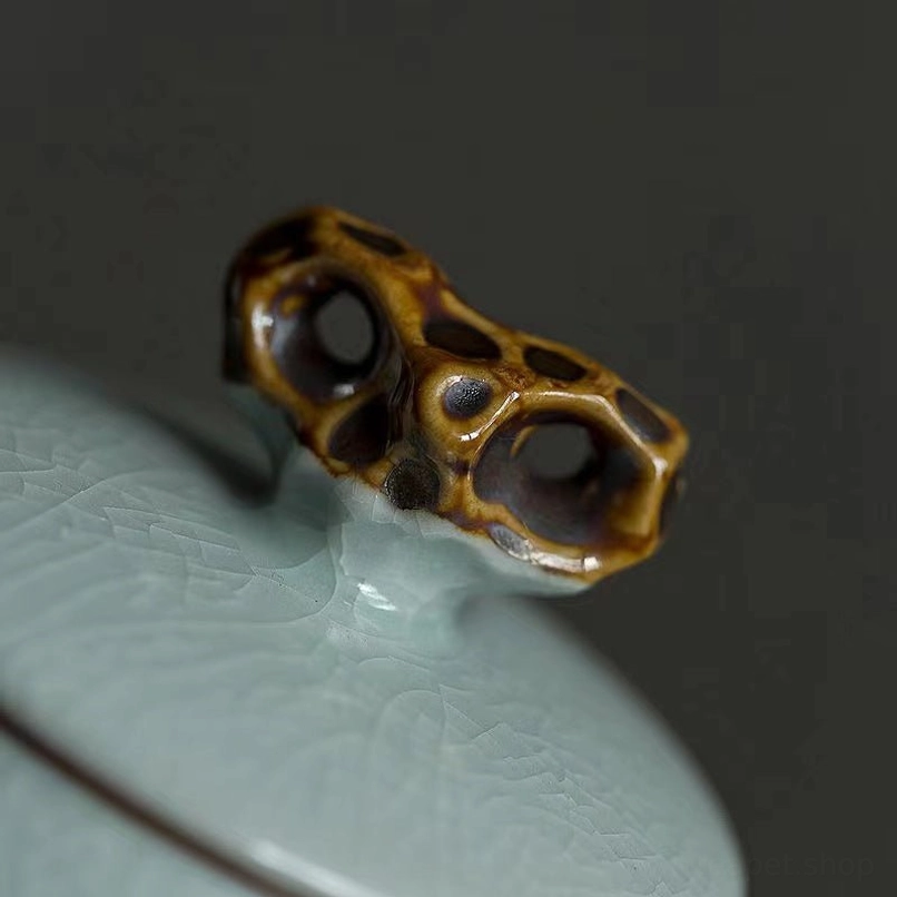 close up of root-shaped knob lid on green ceramic tea jar