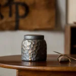Hand hammered charcoal ceramic tea jar with gold accents on display