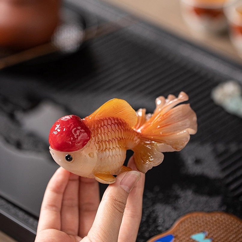 Hand holding lionhead goldfish tea pet to show size and texture