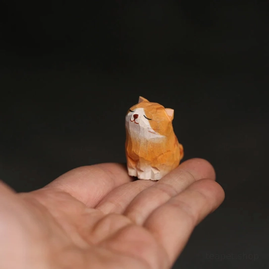Hand holding small wooden cat tea pet demonstrating compact size