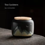 Close-up of black ceramic tea jar with Chinese landscape painting and gold metal lid
