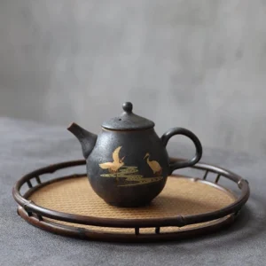 handcrafted black ceramic teapot with gold crane motif front view
