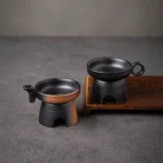 Handcrafted black pottery loose leaf tea strainer on a light background