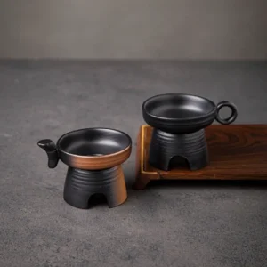 Handcrafted black pottery loose leaf tea strainer on a light background