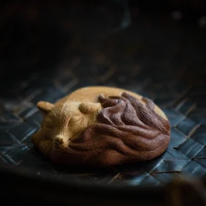 Handcrafted ceramic sleeping nine-tailed fox tea pet full front view on woven mat