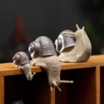 Handcrafted ceramic snail tea pet displayed on wooden bookshelf as rustic home decor