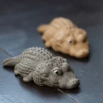 Handmade gray Yixing clay crocodile tea pet displayed on dark wooden tea table