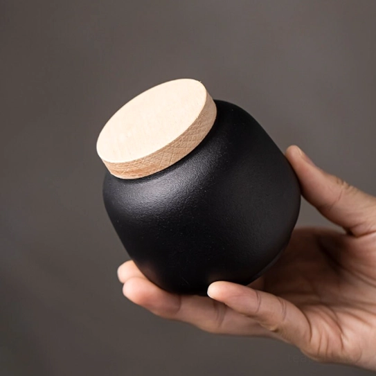 full view of matte black ceramic tea jar with light wood lid