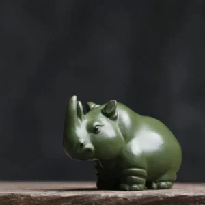 Front view of handmade matte green rhinoceros zisha tea pet on wooden tea table
