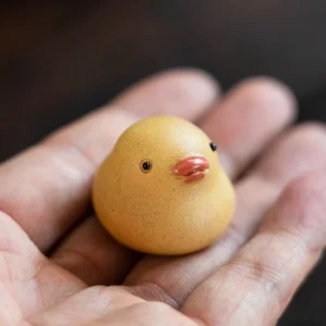 Mini Yixing purple clay duck tea pet held in palm to show tiny size