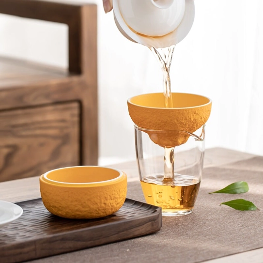 orange loose leaf tea strainer resting on base side view
